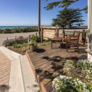 a patio with a table and benches and flowers at Moonstone Cottages in Cambria