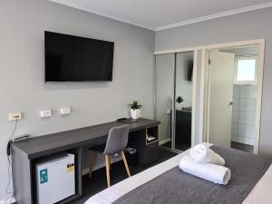 a bedroom with a desk and a television on the wall at Beachway Motel in Ulverstone