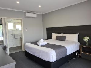a bedroom with a large bed and a bathroom at Beachway Motel in Ulverstone
