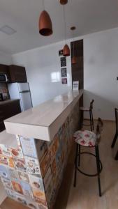 a kitchen with a counter with two chairs and a table at Apartamento mobiliado no centro de paulo afonso in Paulo Afonso