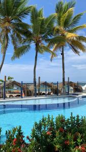 a swimming pool with palm trees in the background at Hotel Portobello in Coveñas