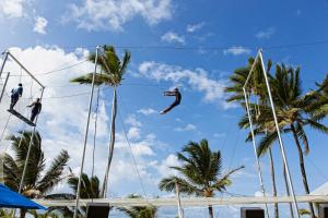 a man jumping from a rope in front of palm trees at Occidental Caribe - All Inclusive in Punta Cana