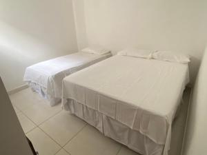 Dos camas en una habitación pequeña con sábanas blancas. en Mellim Residence, en Maragogi