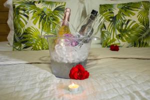 two bottles of champagne and a candle on a bed at Pousada Velosmar in Porto De Galinhas