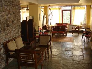 a room with tables and chairs and a stone wall at Valia Calda Hotel in Perivoli