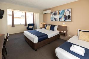 a hotel room with two beds and a chair at The Metropolitan Spring Hill in Brisbane