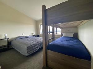 a bedroom with a bunk bed with blue sheets at Tekapo Ski Club Retreat in Lake Tekapo