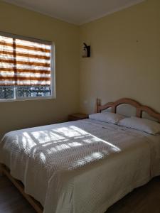 a bedroom with a large white bed with a window at Cabañas Marianela in Bahía Murta