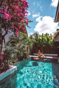 Eine Frau, die auf einem Floß in einem Schwimmbad in einem Resort liegt. in der Unterkunft Beyond Bespoke Villas in Seminyak