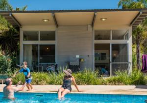 uma família a brincar na piscina de uma casa em Marion Holiday Park em Adelaide