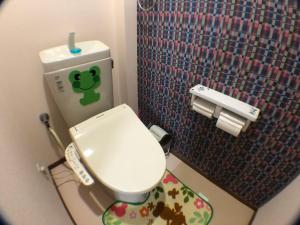 a small bathroom with a toilet with a green sticker on it at Shoyaya Hostel in Osaka