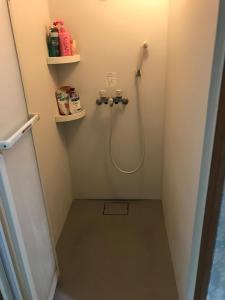 a bathroom with a shower with a hose on the wall at Shoyaya Hostel in Osaka