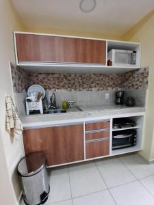 a kitchen with a sink and a microwave at Flat Quartier ao lado Aldeia das Águas in Barra do Piraí