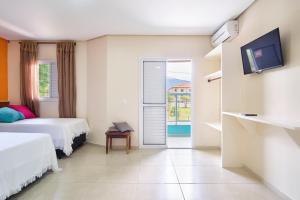 una camera d'albergo con due letti e una porta scorrevole in vetro di Casa do Favacho Suítes a Ubatuba