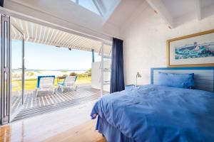 a bedroom with a blue bed and a large window at Friday Island in Langebaan