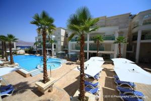 a resort with palm trees and chairs and a swimming pool at YalaRent Palmore Resort apartments in Eilat