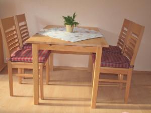 une table en bois avec deux chaises et une plante en pot. dans l'établissement Haus Rosi Göhl, à Bad Hindelang