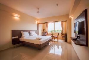 ein Hotelzimmer mit einem Bett und einem TV in der Unterkunft Hotel BMS in Mangaluru