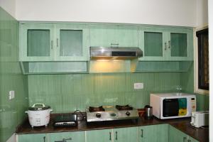 een keuken met groene kasten en een magnetron bij Aishwarya Residency in Tiruvannamalai