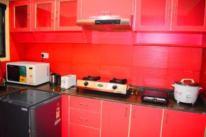 een rode keuken met rode kasten en een magnetron bij Aishwarya Residency in Tiruvannamalai