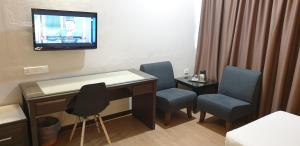 Hotel Samila في ألور سيتار: غرفة بها مكتب وكراسي وتلفزيون على الحائط