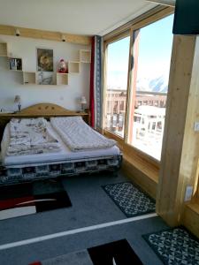 Mâcot La PlagneにあるAppartement d'une chambre a La Plagne Aime 2000 a 10 m des pistes avec vue sur la ville et terrasse amenageeのベッドルーム1室(ベッド1台、大きな窓付)