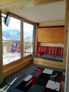 Mâcot La PlagneにあるAppartement d'une chambre a La Plagne Aime 2000 a 10 m des pistes avec vue sur la ville et terrasse amenageeのベッド1台と大きな窓が備わる客室です。