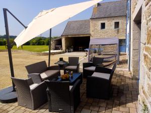 - un ensemble de chaises et d'un parasol sur la terrasse dans l'établissement Maison de 6 chambres avec jacuzzi jardin amenage et wifi a Plougonven, à Plougonven