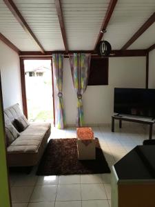 ein Wohnzimmer mit einem Sofa und einem TV in der Unterkunft Maison d'une chambre avec jardin clos et wifi a Le Gosier in Le Gosier