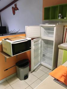 eine Küche mit einem offenen Kühlschrank und einer Mikrowelle in der Unterkunft Maison d'une chambre avec jardin clos et wifi a Le Gosier in Le Gosier