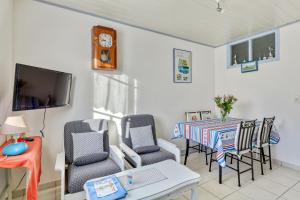 a living room with a table and chairs and a clock at Maison charmante à L'Épine avec jardin clôturé et terrasse in LʼÉpine