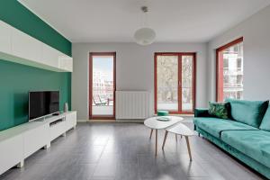 a living room with a green couch and a table at Garnizon Apartments & Free Parking by Downtown Apartments in Gdańsk