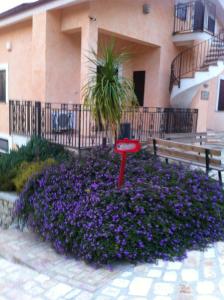 un cartello rosso in un letto di fiori di fronte a un edificio di 5 bedrooms villa with private pool furnished garden and wifi at Bompensiere a Bompensiere