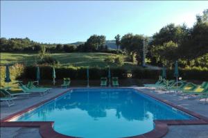 a swimming pool with chairs and a golf course at Cozy House in Caprese Michelangelo + Pool in Arezzo +12 photos