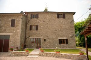 a large stone house with a stone wall at Cozy House in Caprese Michelangelo + Pool in Arezzo