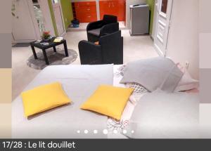 een wit bed met 2 gele kussens erop bij Studio avec jardin amenage et wifi a Le Marin a 3 km de la plage in Le Marin