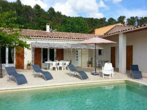 uma casa com uma piscina e cadeiras e um guarda-sol em Villa de 4 chambres avec piscine privee et jardin clos a Le Beaucet em Le Beaucet