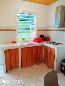 a kitchen with a sink and a stove and a window at Maison d'une chambre avec piscine partagee terrasse amenagee et wifi a Petit Bourg in Petit-Bourg