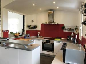 une cuisine avec des placards blancs et un mur rouge dans l'établissement Villa de 3 chambres avec piscine privee jardin clos et wifi a Pietralba, à Pietralba