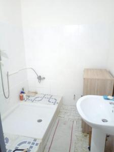 uma casa de banho branca com uma banheira e um lavatório em Maison de 2 chambres avec jardin clos a Basse Terre em Basse-Terre