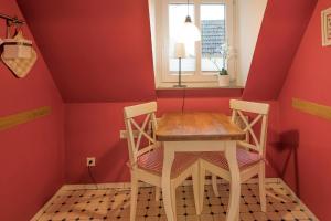 einen Tisch und Stühle in einem Zimmer mit roten Wänden in der Unterkunft Dat lütte Huus - Wohnung 1 in Husum
