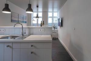 a white kitchen with a sink and a counter at Apartmenthaus Theodor Storm Dämmerstunde in Husum +5 photos
