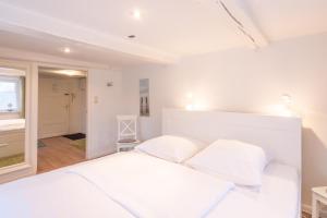 a white bedroom with a bed with two pillows at Apartmenthaus Tönning Kleine Kajüte in Tönning