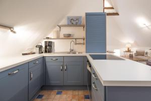 a kitchen with blue cabinets and a sink at Beach-Loft in Wobbenbüll