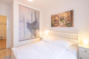 テニングにあるApartmenthaus Tönning Strandmuschelの白いベッド1台、壁に絵画2点が備わるベッドルーム1室