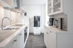 cocina blanca con fregadero y nevera en Apartmenthaus Theodor Storm Meeresstrand, en Husum