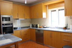 a kitchen with wooden cabinets and stainless steel appliances at 3 bedrooms villa with private pool furnished garden and wifi at Sao Martinho de Mouros 1 km away from the beach in Frende