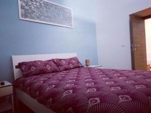 un letto con piumone viola in una camera da letto di Theatron Houses a Catania