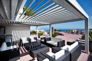 eine Terrasse mit weißen Stühlen und Tischen auf dem Dach in der Unterkunft Hotel Desenzano in Desenzano del Garda