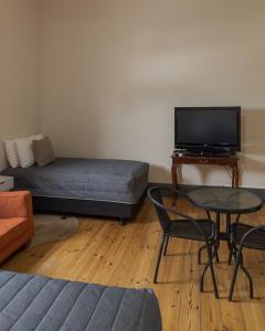 uma sala de estar com uma cama, uma mesa e uma televisão em Pampas Motel Port Augusta em Port Augusta